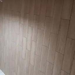 Wykończona łazienka z połączeniem białych, kwadratowych płytek i drewnopodobnych paneli ściennych ułożonych pionowo.