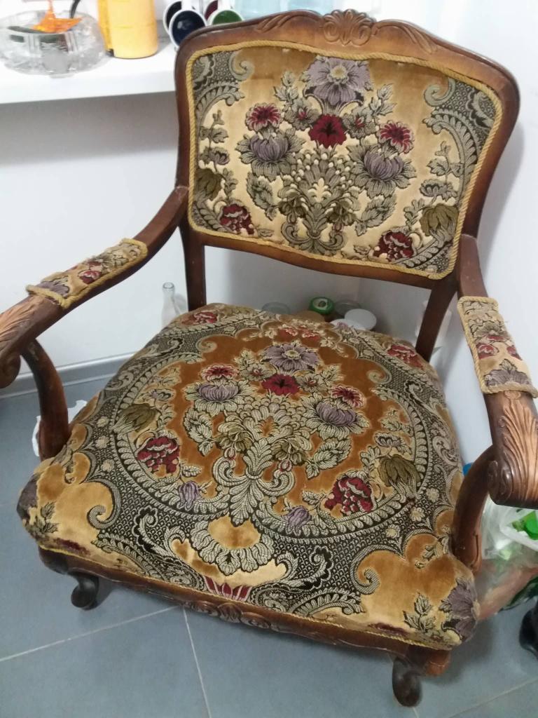 Antyczny fotel z kwiatowym wzorem tapicerki, widoczny w Białymstoku, z drewnianymi, rzeźbionymi elementami ramy.
