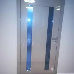 Szklane drzwi wewnętrzne z dwoma pionowymi, niebieskimi pasami, zamontowane w jasnym pomieszczeniu z czarno-białą podłogą.