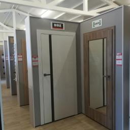 Bopan Żurawski Artur Żurawska Katarzyna S.C. - Ekspozycja modeli drzwi wewnętrznych DRE i Porta w salonie, widoczne różne style i wykończenia, podłoga z paneli imitujących drewno.