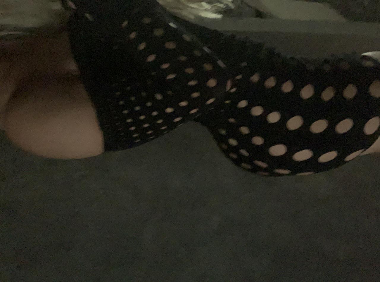 Czarna, ażurowa tkanina z białymi kropkami, być może element dekoracji lub kostiumu, na ciemnym tle.