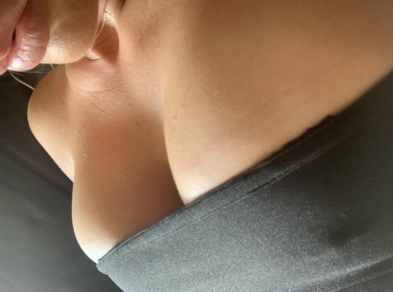 Nietypowy kadr z bliska na dekolt kobiety w sportowym topie z widocznym łańcuszkiem na szyi.