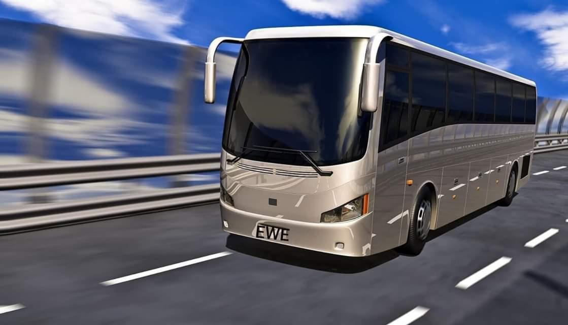 Srebrny autokar z napisem 'EWE' na tablicy rejestracyjnej, pędzący po autostradzie w słoneczny dzień.