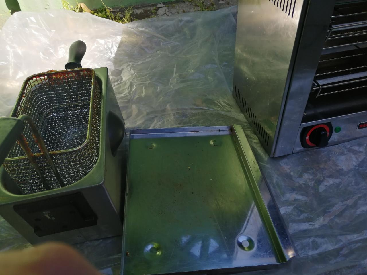 Brudna frytownica i piekarnik po użyciu, widoczne ślady tłuszczu i resztek jedzenia, umieszczone na folii ochronnej.