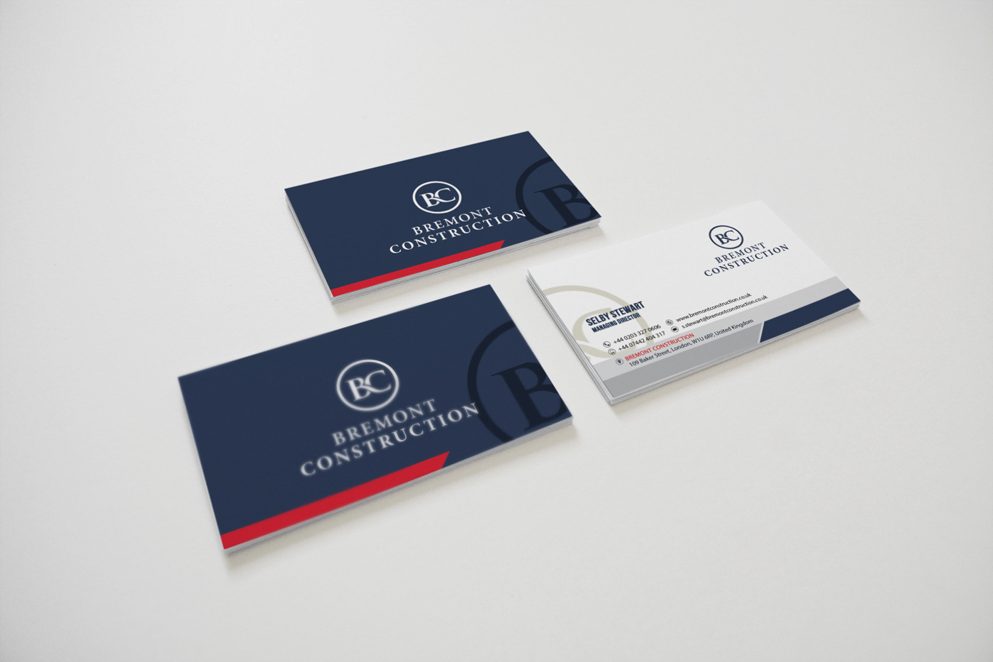 Wizytówki Bremont Construction: dwie granatowe z czerwonym akcentem i logo BC, jedna biała z danymi kontaktowymi Selby Stewart.