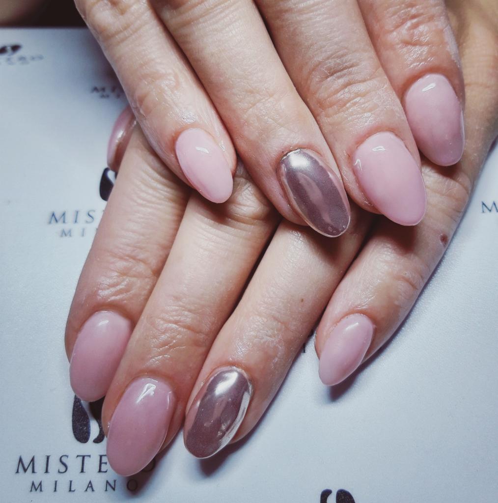 Dłonie z owalnymi paznokciami w odcieniach pudrowego różu i metalicznego brązu na tle logo MISTE MILANO.