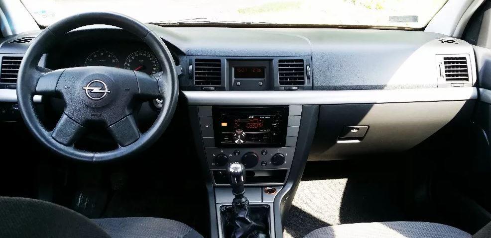 Wnętrze samochodu Opel Vectra C, widok na deskę rozdzielczą, kierownicę z logo, radio JVC i panel klimatyzacji.