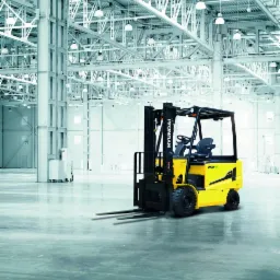 Żółty wózek widłowy Hyundai 25B-9 na tle hali magazynowej z metalową konstrukcją stropu i betonową podłogą.