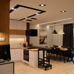 Nowoczesne wnętrze: kuchnia z wyspą i jadalnią, oświetlenie punktowe i dekoracyjne, drewniane akcenty i minimalistyczny design, widok na miasto z balkonu.