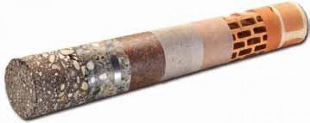 Przekrój rdzenia wiertniczego prezentujący warstwy betonu, gruntu, cegły i innych materiałów budowlanych.