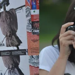 Dwóch fotografów z aparatami fotograficznymi, jeden mężczyzna fotografuje na tle budynku z plakatem, druga kobieta fotografuje z bliska z rozmazanym tłem.