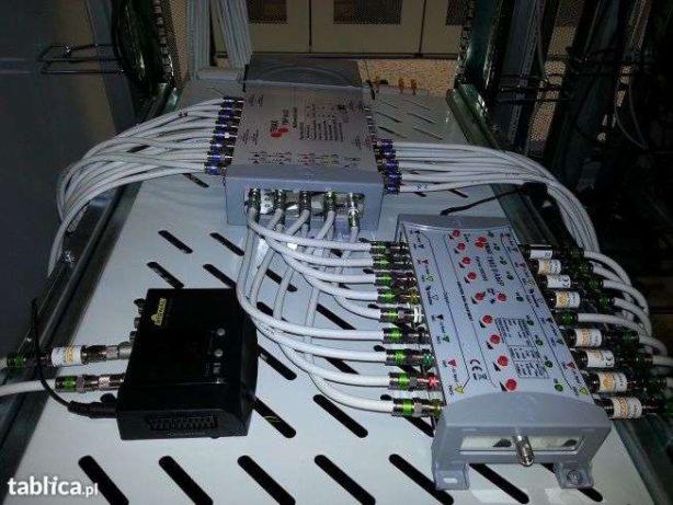 Rozdzielacz sygnału antenowego z podłączonymi kablami koncentrycznymi, widoczne złącza F i etykiety na kablach.