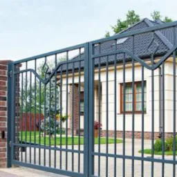 Elegancka, metalowa brama wjazdowa z dekoracyjnymi elementami i murowanymi słupkami z cegły, na których widnieje nazwa ulicy 'Topolowa', prowadząca do domu z szarym dachem.