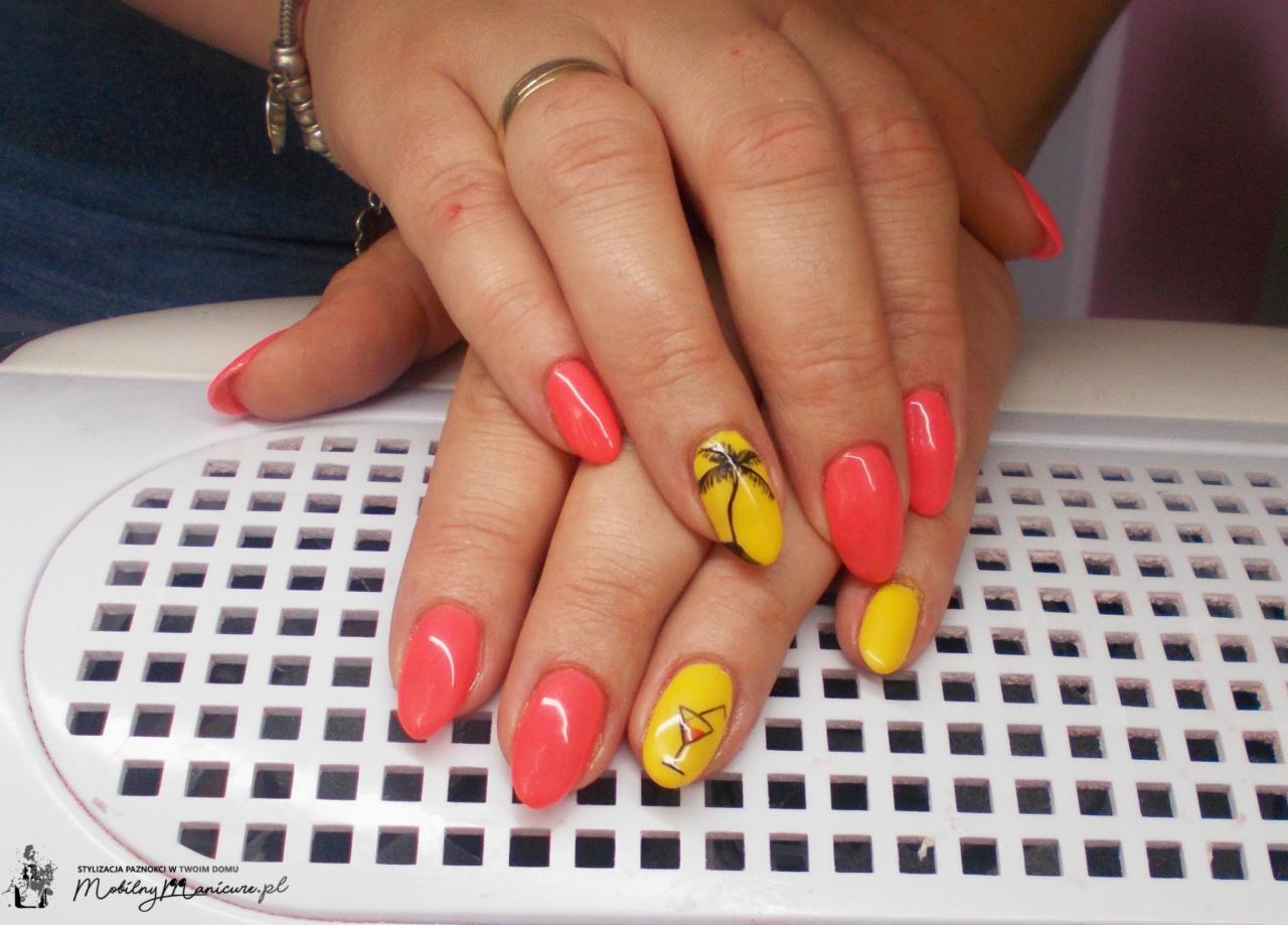 Dłonie z pomalowanymi paznokciami w odcieniach koralu i żółci, z motywem palmy i drinka, na białym tle lampy UV do manicure.