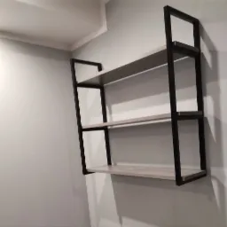 Trzy półki z czarną metalową ramą przymocowane do szarej ściany, widoczne z boku.