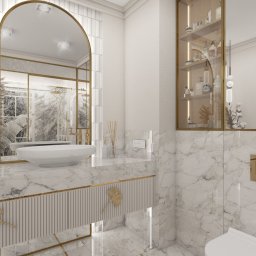 AM_projektowanie - Elegancka łazienka w bieli i marmurze z akcentami złota: umywalka nablatowa, lustro w łuku, szafka z ryflowanym frontem i dekoracyjnymi uchwytami.