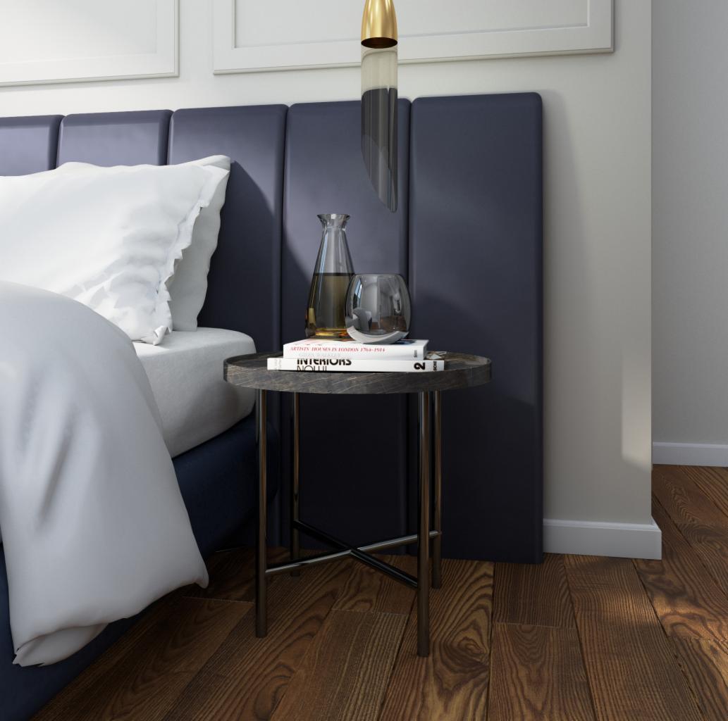 Sypialnia z nocnym stolikiem w stylu modern classic, na którym stoją książki, szklany wazon i dekoracyjny kielich, oświetlona wiszącą lampą z elementami złota.