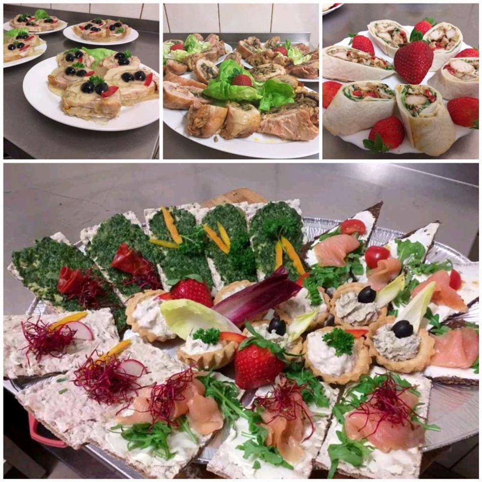 Różnorodne przekąski na srebrnej tacy i białych talerzach: kanapki z łososiem i rukolą, tartaletki z kremowym nadzieniem, wrapy z kurczakiem i warzywami, roladki mięsne z zielonymi dodatkami...