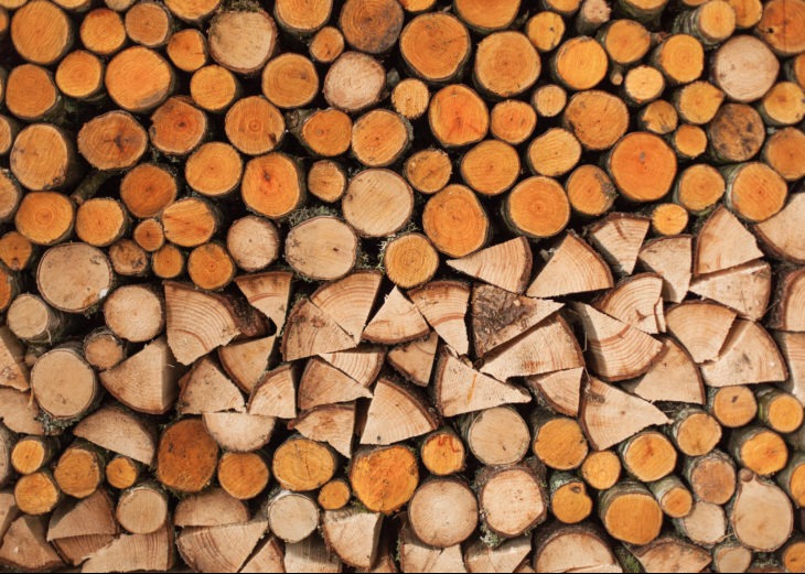 Równomiernie ułożony stos okrąglaków i porąbanego drewna, widoczne słoje drzewa i fragmenty kory.