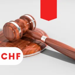 Drewniany młotek sędziowski z srebrnymi obręczami, leżący na okrągłej podstawce, z napisem '#CHF' w rogu i czerwoną wstążką w tle.