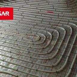 Białe rury ogrzewania podłogowego ułożone na siatce w kratkę, z widocznym logo firmy VINSAR w lewym górnym rogu.