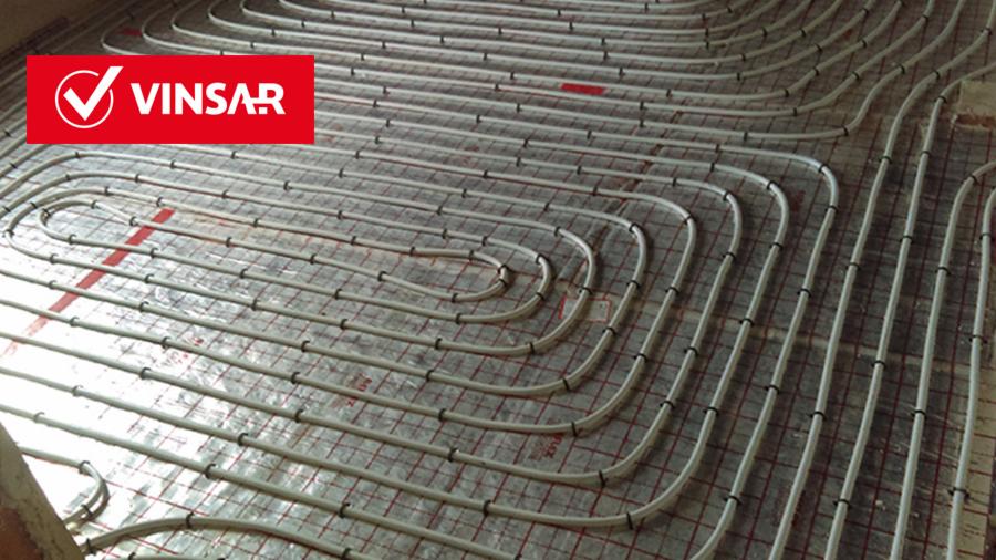 Białe rury ogrzewania podłogowego ułożone na siatce w kratkę, z widocznym logo firmy VINSAR w lewym górnym rogu.
