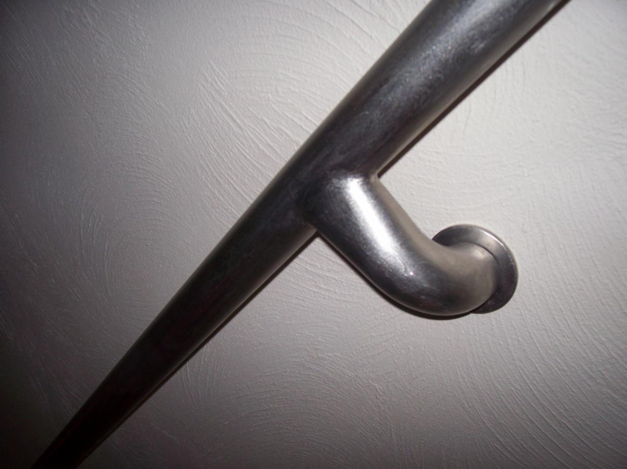 Metalowa poręcz przymocowana do ściany o wyraźnej fakturze, widoczna z bliska.