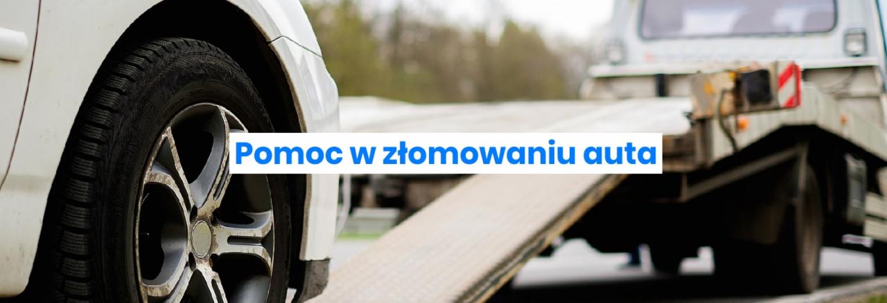 Fragment białego samochodu z widocznym kołem i oponą zimową, w tle laweta z najazdami przygotowana do transportu pojazdu.
