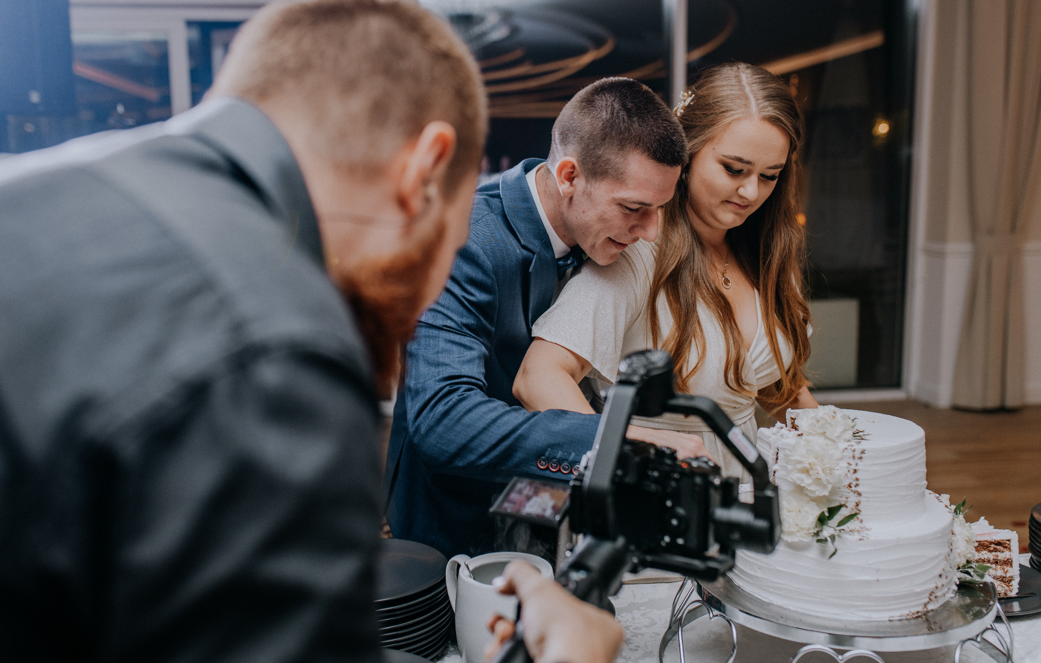 Młoda para kroi tort weselny, filmowana z bliska przez kamerzystę z użyciem gimbala.