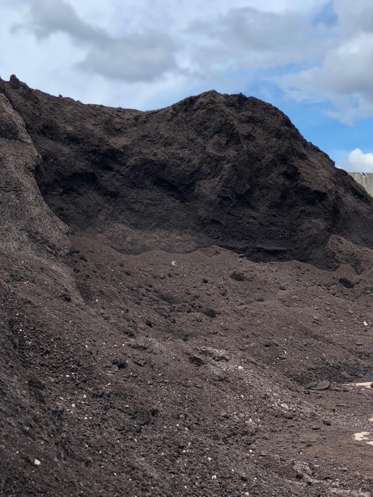 Góra usypanej ziemi z widocznymi grudkami i kamieniami, na tle błękitnego nieba z chmurami.