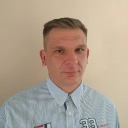 Portret mężczyzny w koszuli w paski, Lublin. Widoczny fragment koszuli z napisem '33 DIVISION'. Neutralne tło, oświetlenie naturalne, brak elementów rozpraszających.