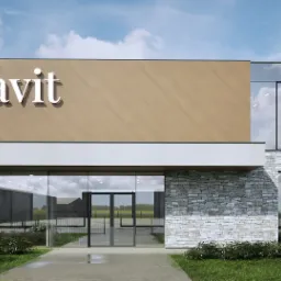 Wizualizacja budynku usługowego z elementami kamiennej elewacji, dużymi szklanymi oknami i logo 'avit' na beżowej ścianie. Widoczne odbicie chmur w szybach i fragment zieleni na pierwszym planie.