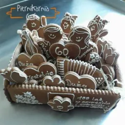 Kosz z pierników dekorowanych białym lukrem, w kształcie serc, postaci i harmonijki, z napisami okolicznościowymi.