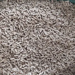 Jasnobrązowe granulki opału drzewnego, widoczne z góry, wypełniające całą przestrzeń kadru.