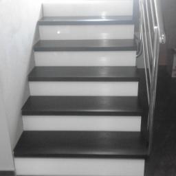 rubin - Odnowione schody z ciemnymi stopniami i białymi podstopnicami, widoczne metalowe poręcze i fragment ściany.