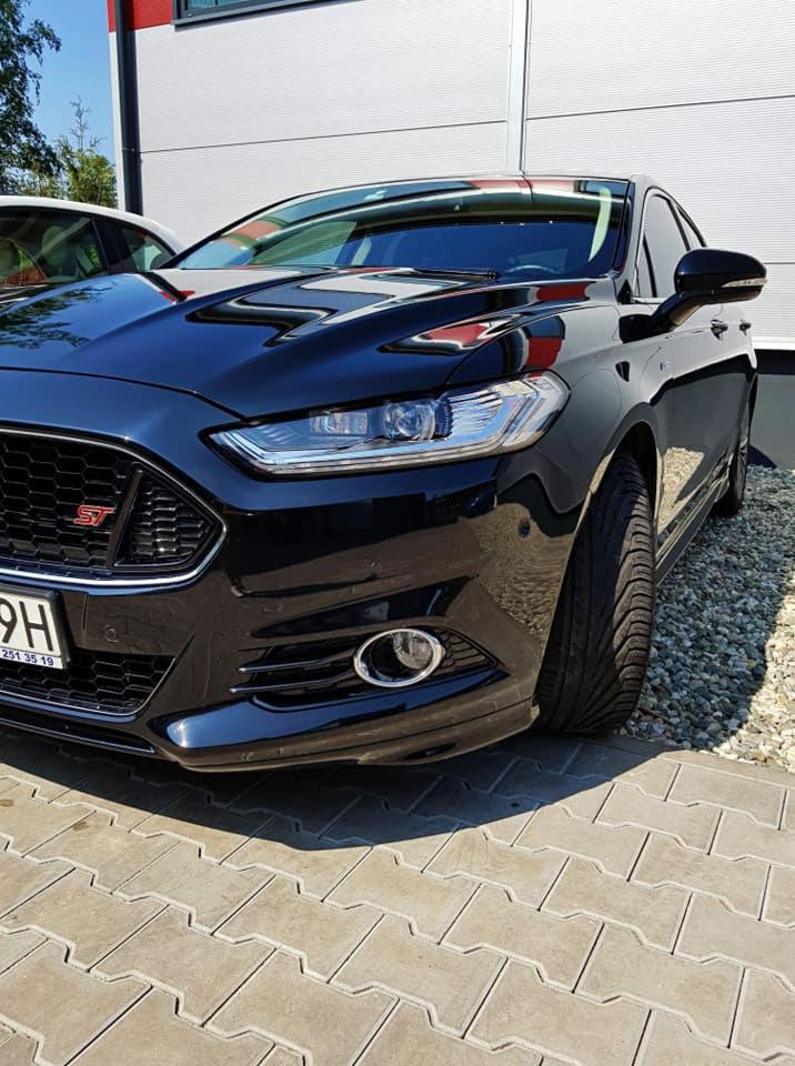 Błyszczący, czarny Ford Mondeo ST po umyciu, zaparkowany na kostce brukowej z widocznym żwirem