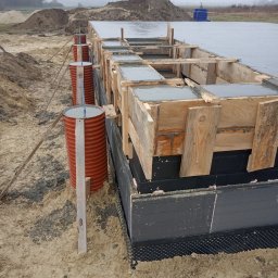ARTUR SZMALEC Specjalistyczne Usługi Budowalne - Wylany beton w szalunku fundamentowym z izolacją pionową, wsparty na ziemi za pomocą beczek i drewnianych rozpórek.
