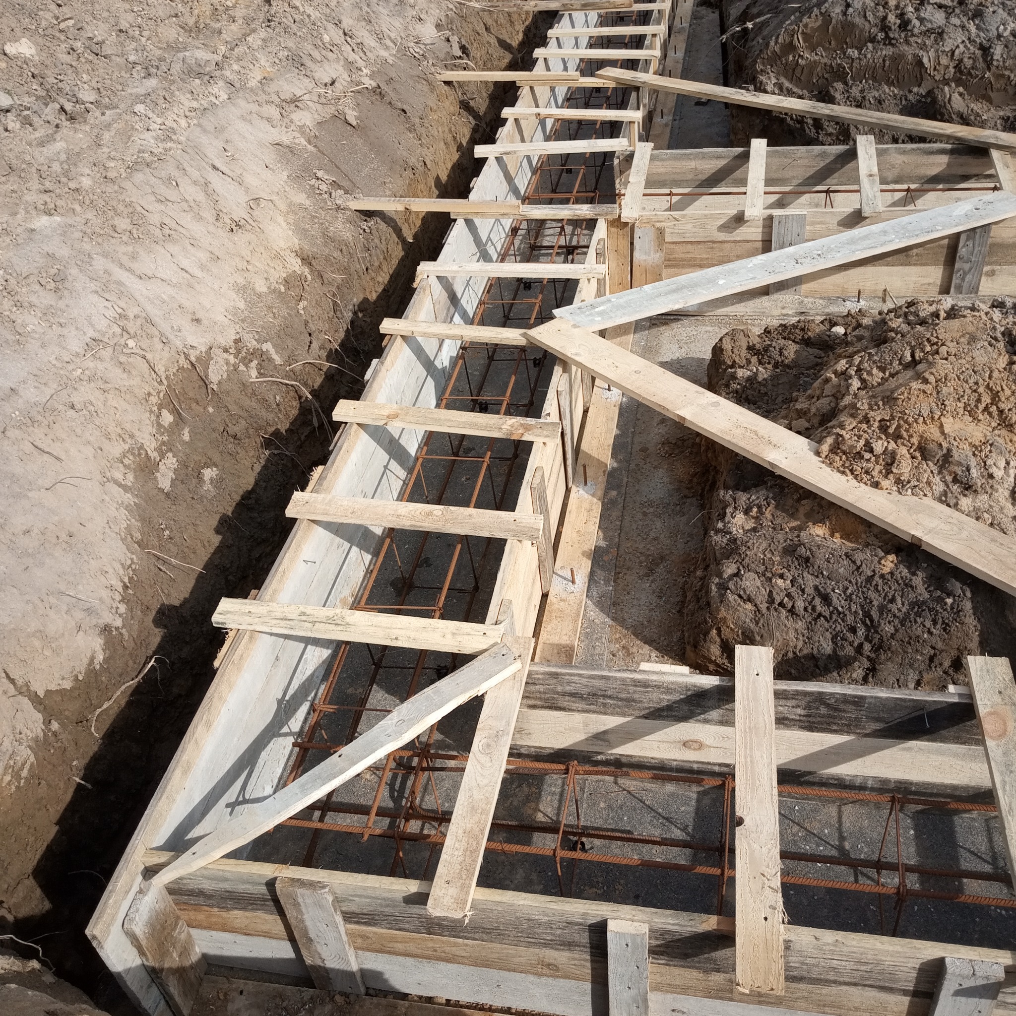 Wykop z szalunkiem i zbrojeniem przygotowany pod wylanie fundamentów, widok z góry.