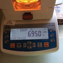 Analizator wilgotności MA 50.R w trakcie procesu suszenia próbki, wyświetlający wynik 6.950% na ekranie LCD.