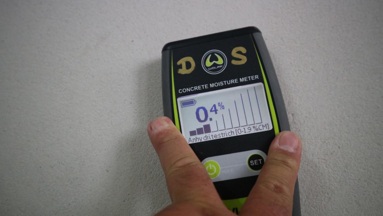 Pomiar wilgotności anhydrytowej wylewki za pomocą elektronicznego wilgotnościomierza marki DOS Wolff, wskazującego 0.4% wilgotności.