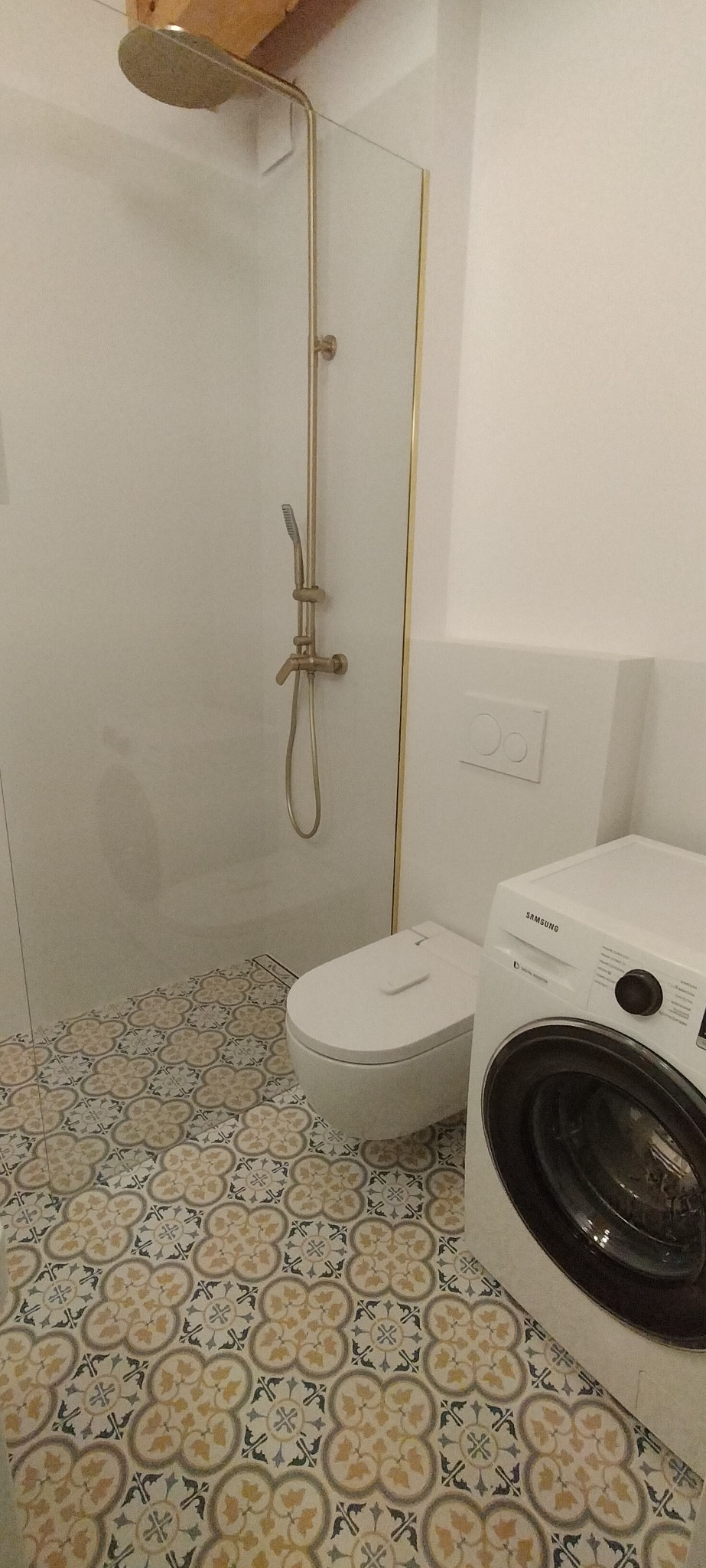 Nowoczesna łazienka z kabiną prysznicową typu walk-in z złotymi elementami, toaletą myjącą i pralką Samsung, wykończona płytkami podłogowymi w stylu retro.