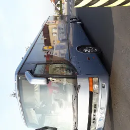Szary autokar SETRA na parkingu z widocznym odbiciem budynku w szybach.