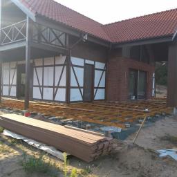 Usługi Remontowo Budowlane Krzysztof Królik - Budowa tarasu przy domu z elementami muru pruskiego i ceglaną elewacją, widoczne drewniane legary i deski tarasowe czekające na montaż.