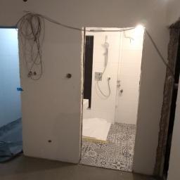 Usługi Remontowo Budowlane Krzysztof Królik - Remontowana łazienka w Gajówce natalin z widoczną nową, wzorzystą podłogą i przygotowaną kabiną prysznicową, instalacja elektryczna na ścianie.