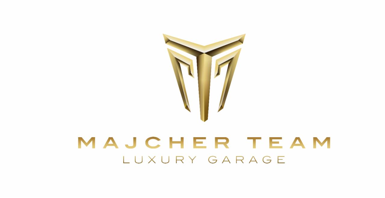 Złote logo firmy 'Majcher Team Luxury Garage' na białym tle, przedstawiające geometryczny symbol przypominający literę 'M' w formie trójwymiarowej strzałki skierowanej w dół.