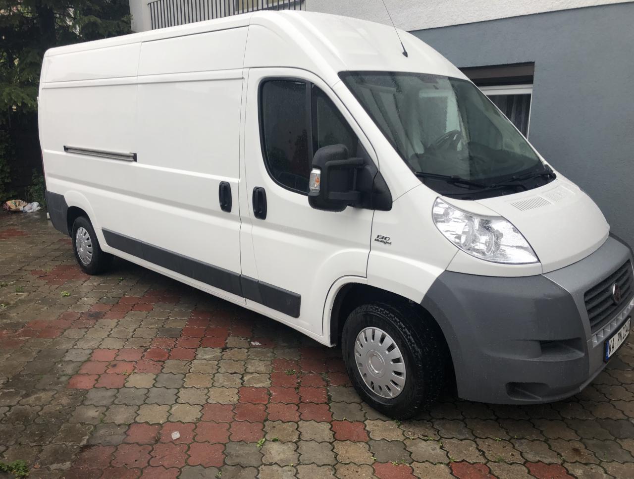 Biały bus dostawczy Fiat Ducato 130 Multijet zaparkowany na kostce brukowej w pochmurny dzień, widoczny z boku.