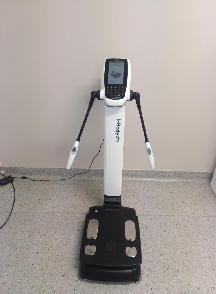 Analizator składu ciała InBody 270, czarno-biały, z ekranem dotykowym i elektrodami, ustawiony na tle jasnej ściany i podłogi z terazzo.