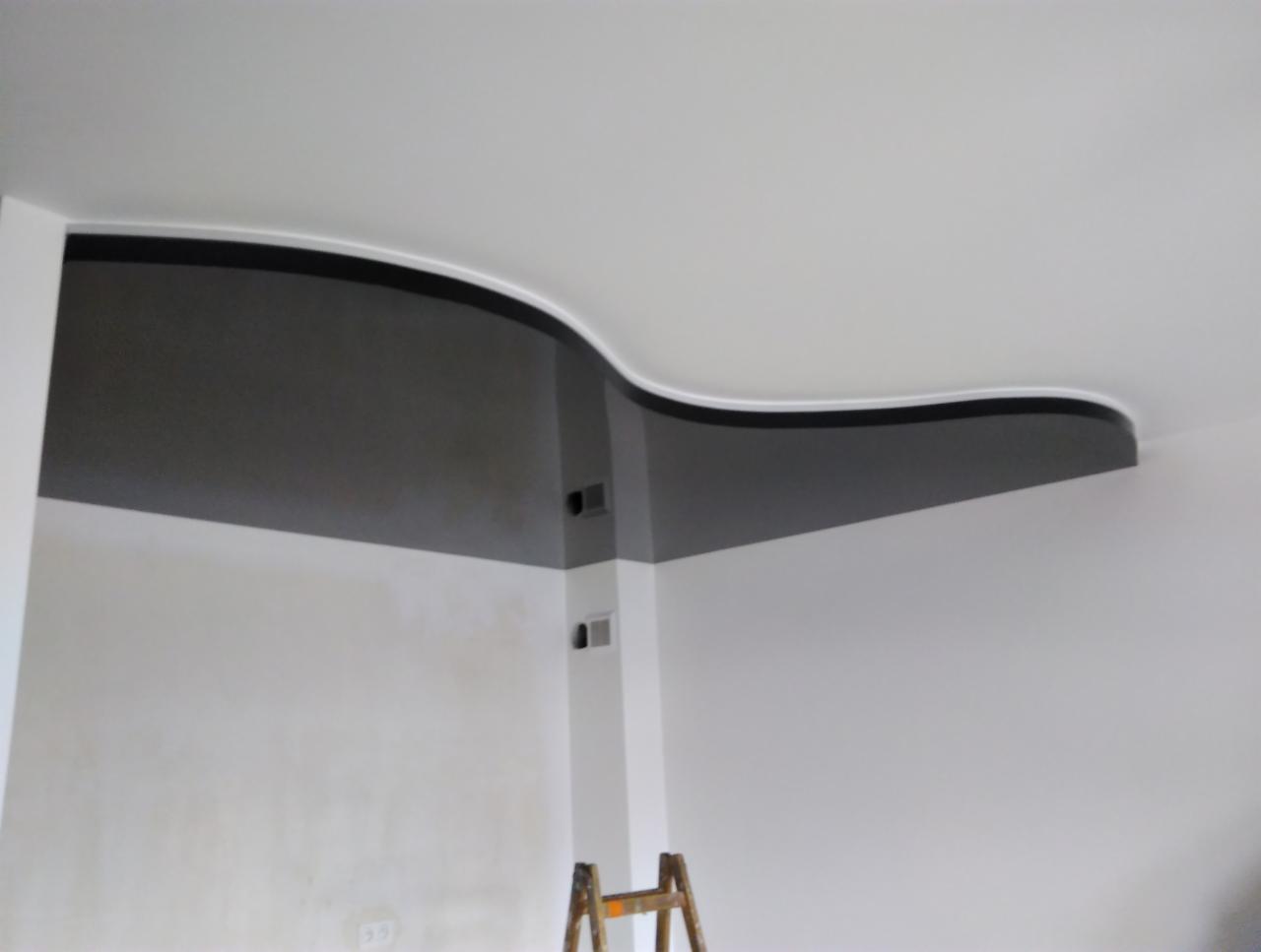 Wykończony fragment wnętrza z pomalowaną na szaro, falistą dekoracją pod sufitem, widoczna drabina malarska.