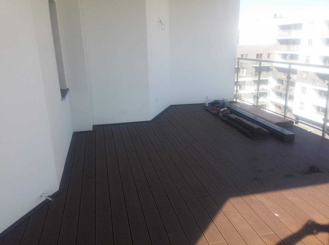 Montaż tarasu kompozytowego na balkonie, widoczne profile i narzędzia przed ukończeniem prac.