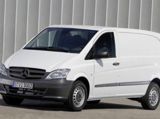 Biały samochód dostawczy Mercedes-Benz Vito z ciemnoszarym zderzakiem i numerem rejestracyjnym S VI 5002, zaparkowany na tle szarej ściany z pionowymi panelami.